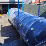 Oversized industrial cargo lowered by crane into vessel hold for project logistics shipment