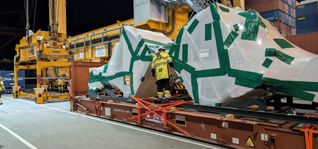 Night-time cargo operations at the Port of Helsinki with oversized industrial equipment prepared and secured for overseas transportation.