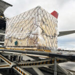Crated industrial equipment secured on an air cargo platform before departure from Finland to Japan.