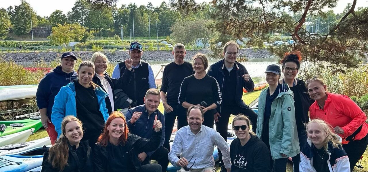 Volunteers gathered with collected waste after a Baltic Sea Day shoreline clean-up, posing beside kayaks and bags of litter removed from the Baltic Sea environment.
