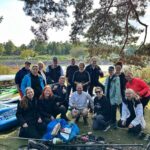 Volunteers gathered with collected waste after a Baltic Sea Day shoreline clean-up, posing beside kayaks and bags of litter removed from the Baltic Sea environment.