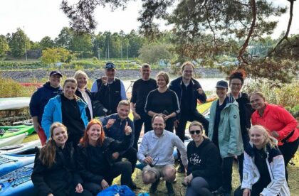 Volunteers gathered with collected waste after a Baltic Sea Day shoreline clean-up, posing beside kayaks and bags of litter removed from the Baltic Sea environment.