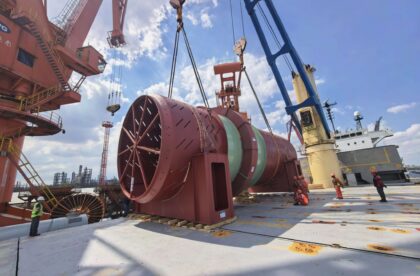 170-ton industrial drum secured on the deck of a heavy-lift vessel while cranes and stevedores complete cargo handling operations at the port.